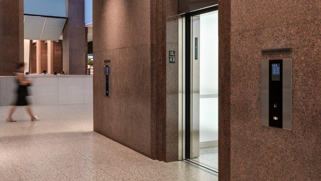 Commercial plaza lobby with granite walls and an open elevator entrance