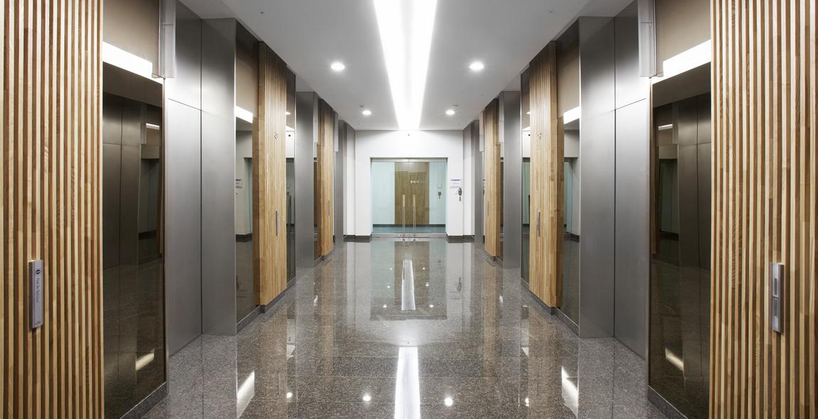 Office complex corridor lined with wood-slat panels and multiple elevators